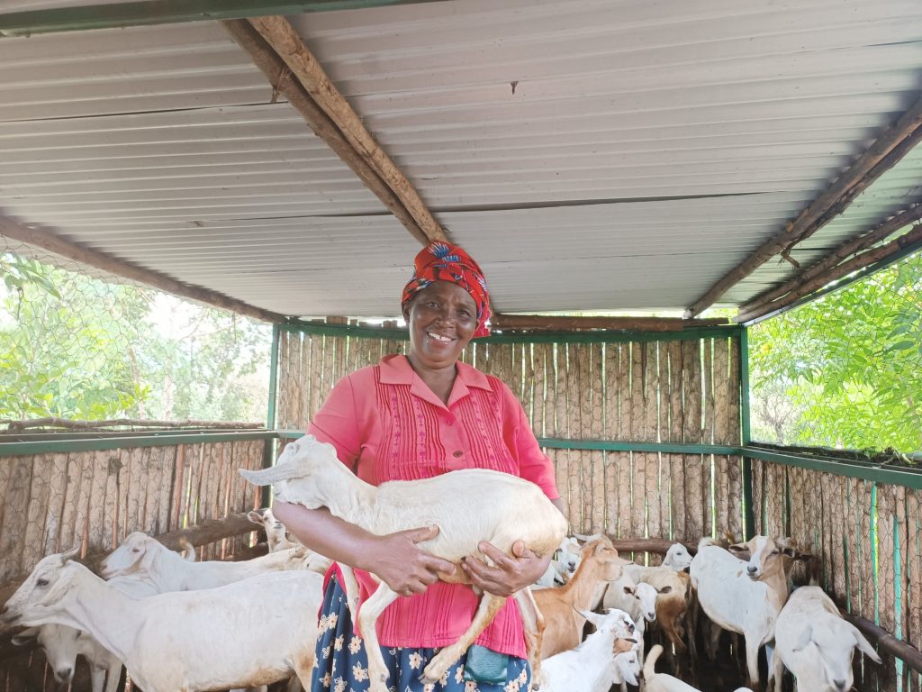 A woman stood smiling while holding a goat